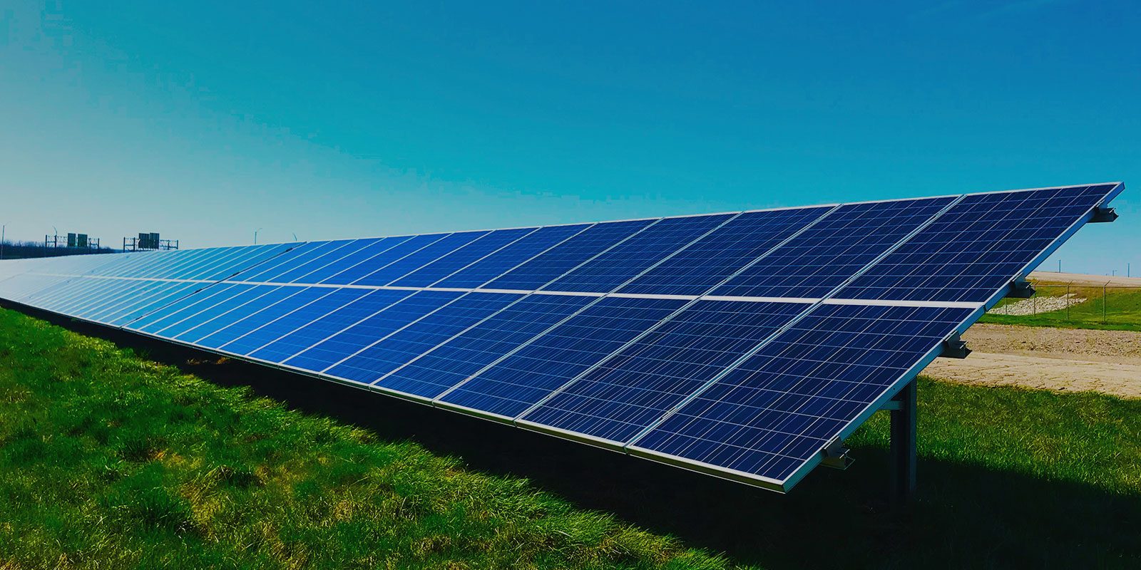 Solarpark mit blauen Modulreihen vor grüner Wiese